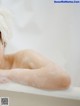 A woman laying in a bathtub covered in foam.