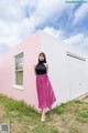 A woman standing in front of a pink building.