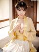 A woman in a yellow kimono sitting on a bed.