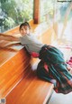 A young girl leaning on a wooden bench.