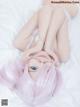 A woman with pink hair laying on a bed.