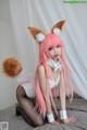 A woman with long pink hair wearing a fox costume.