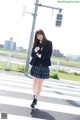 A woman in a school uniform is crossing the street.