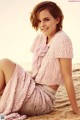 A woman in a pink dress sitting on the beach.