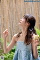 A woman in a blue dress holding a piece of cake.
