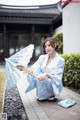 A woman in a blue kimono holding an umbrella.