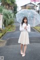 A woman standing in the middle of a street holding an umbrella.