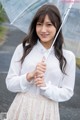 A woman in a white shirt holding an umbrella.