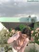 A woman standing in front of a bunch of flowers.