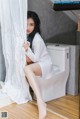 A woman sitting on a toilet in a bathroom.