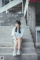 A woman sitting on the steps of an abandoned building.