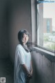 A woman standing by a window in an abandoned building.