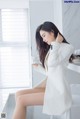 A woman in a white suit sitting on a white chair.