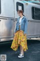 A woman standing in front of a trailer wearing a yellow floral skirt.