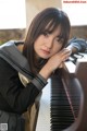 A woman in a school uniform leaning on a piano.