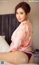 A woman sitting on top of a bed in a pink shirt.