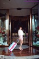 A woman in a pink dress with a pink suitcase.