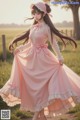 A woman in a pink dress is standing in a field.