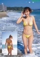 A woman in a yellow bikini standing in the ocean.