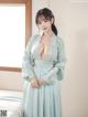 A woman in a blue robe standing on a bed.