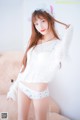 A woman in a white sweater and panties posing for a picture.