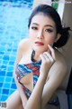 A woman in a colorful bikini sitting by a pool.