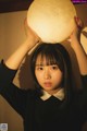 A woman holding a large moon lamp over her head.