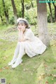 A woman in a white dress sitting under a tree.