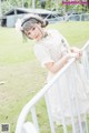 A woman in a white dress standing next to a white railing.